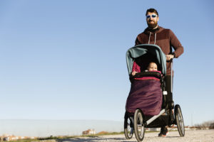 Man running behind a jogging stroller with a child inside