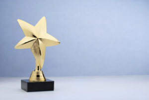 Golden star trophy sitting on a white table with a blue background